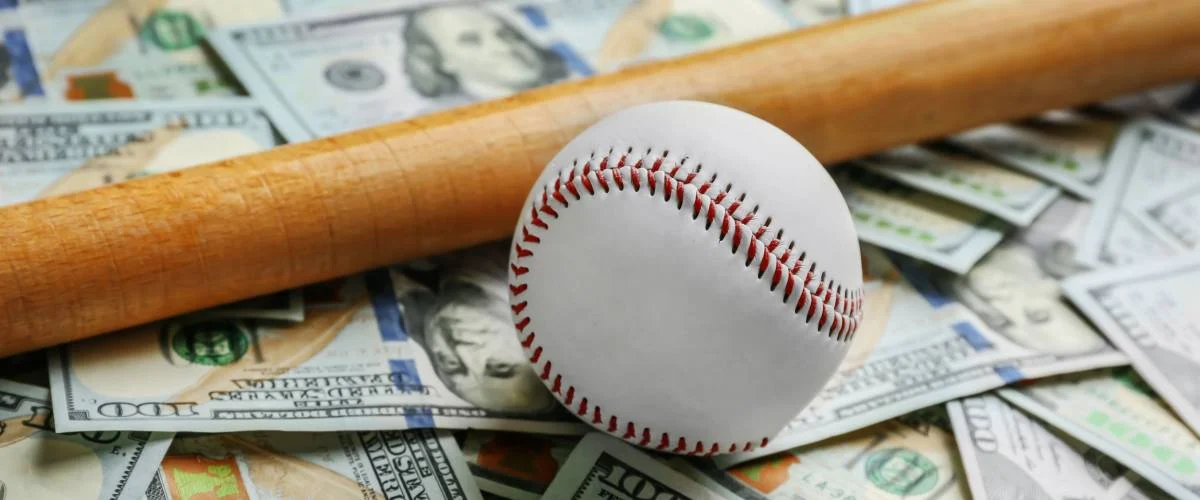 Baseball and bat on a pile of $100 American currency