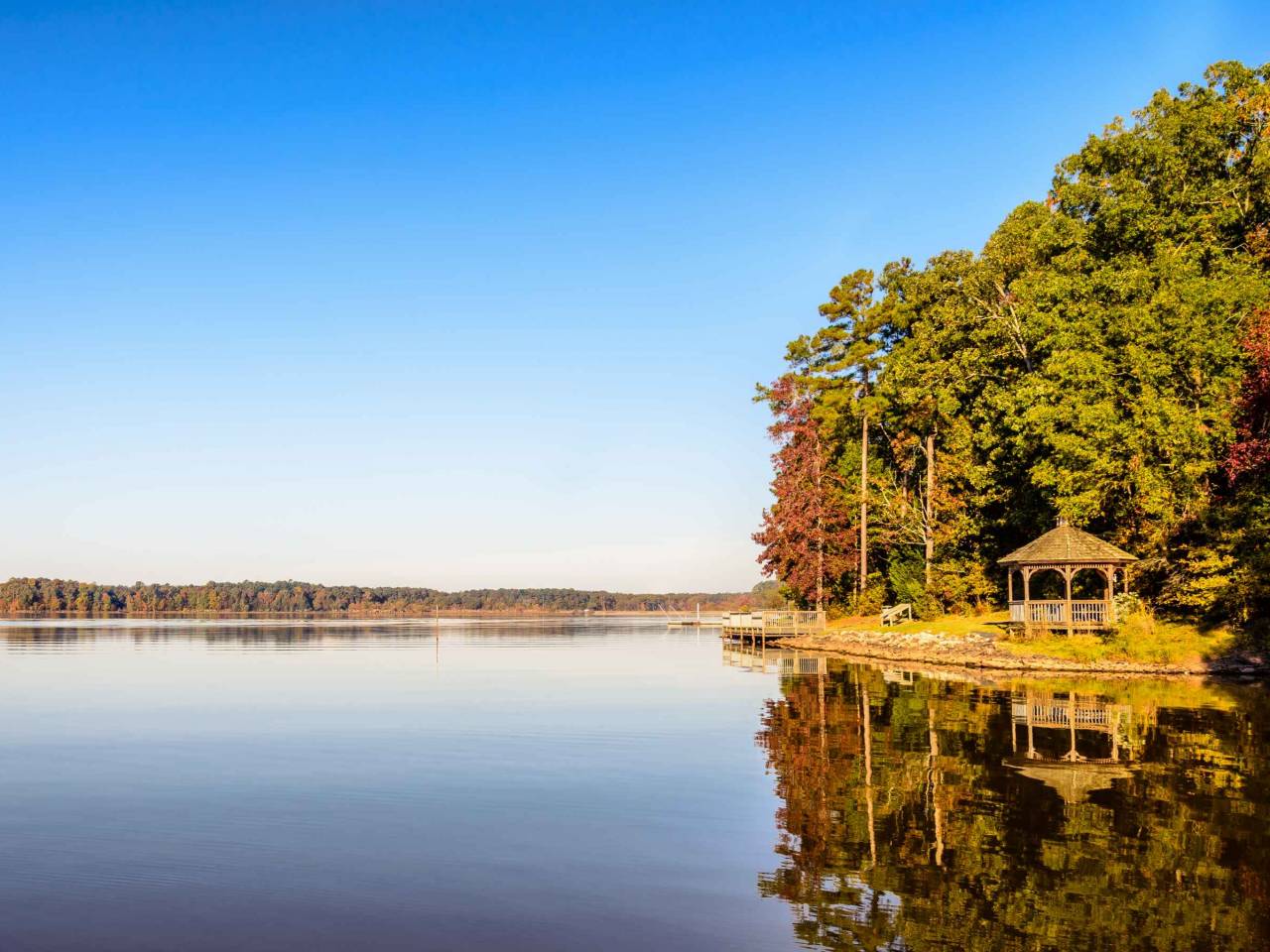 Still and clear waters of Lake Crabtree in Morrisville, North Carolina has captured the beautiful reflection of the land, trees and the clear blue sky.